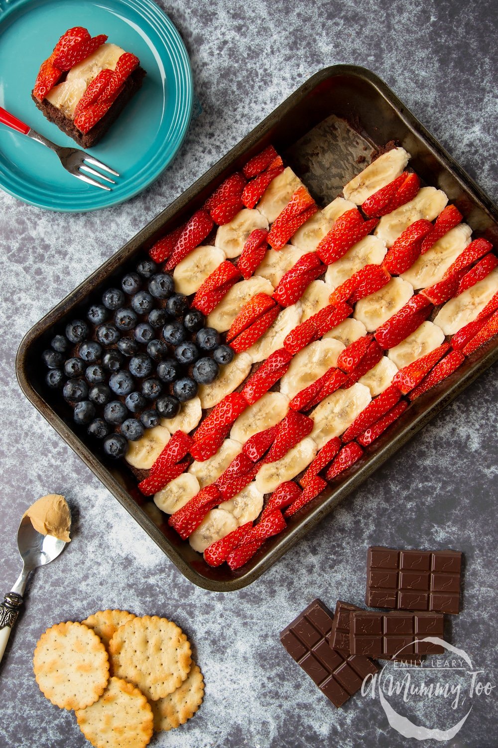 A plate with a section of the peanut butter brownies in the shape of the American flag for the 4th of July alongside the remaining peanut butter brownies tin.