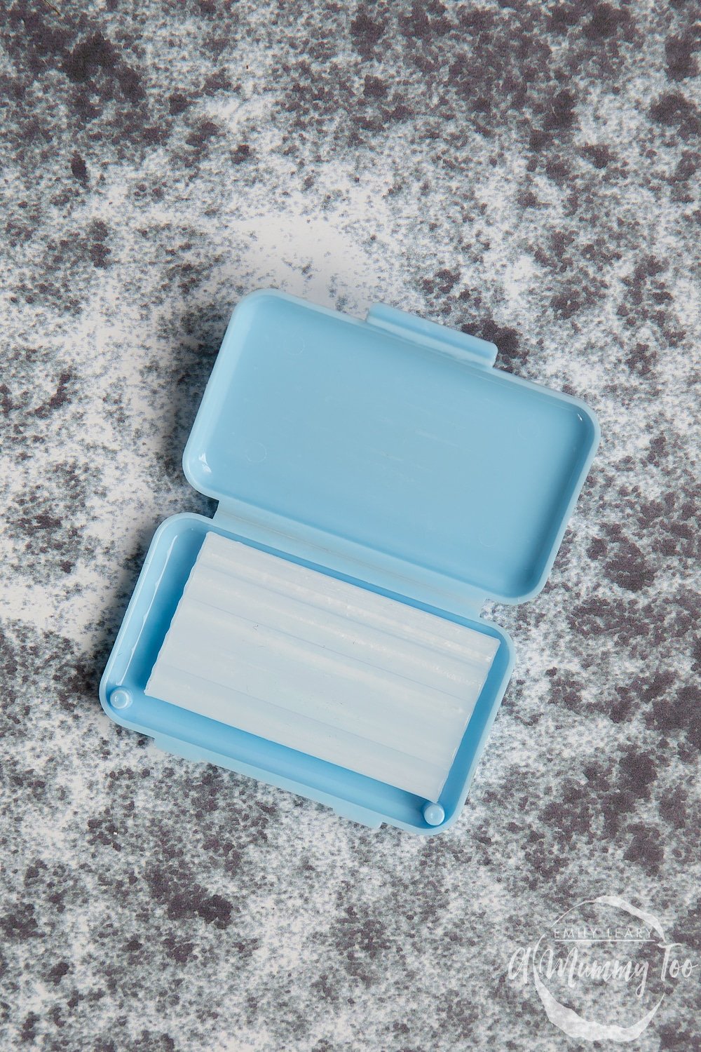 small pale blue box of dental wax on a grey background
