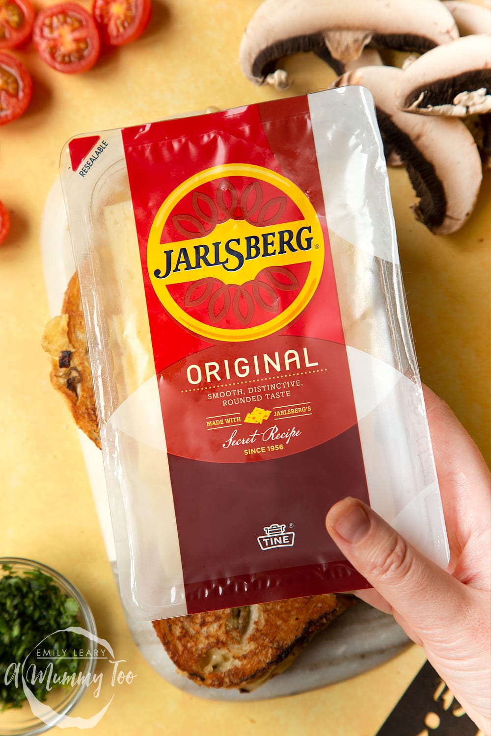 A packet of Jarlsberg cheese is being held up, two mushroom toasties are also on the table.