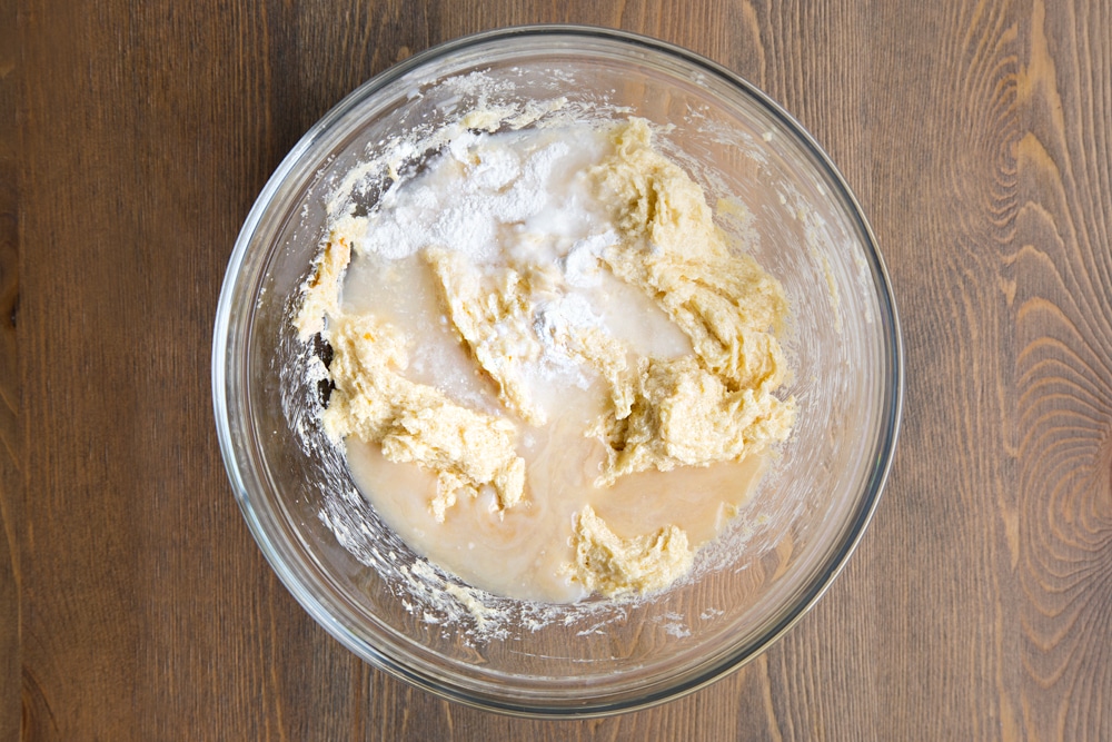 Butter and sugar creamed together in a bowl, with milk, egg replacement powder and vanilla extract on top.