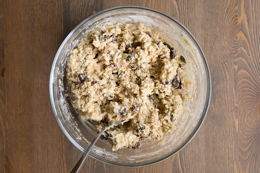 Vegan oat cookie dough with chocolate, seeds and raisins on top.