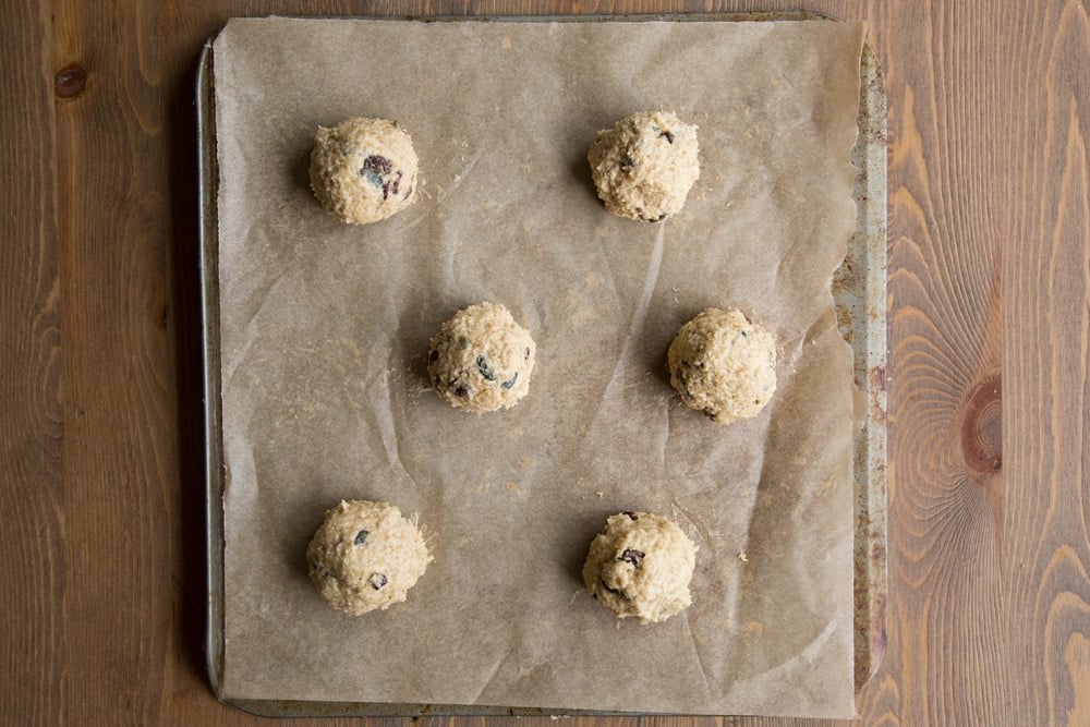 Balls of vegan oat cookie dough on a tray lined with baking paper.