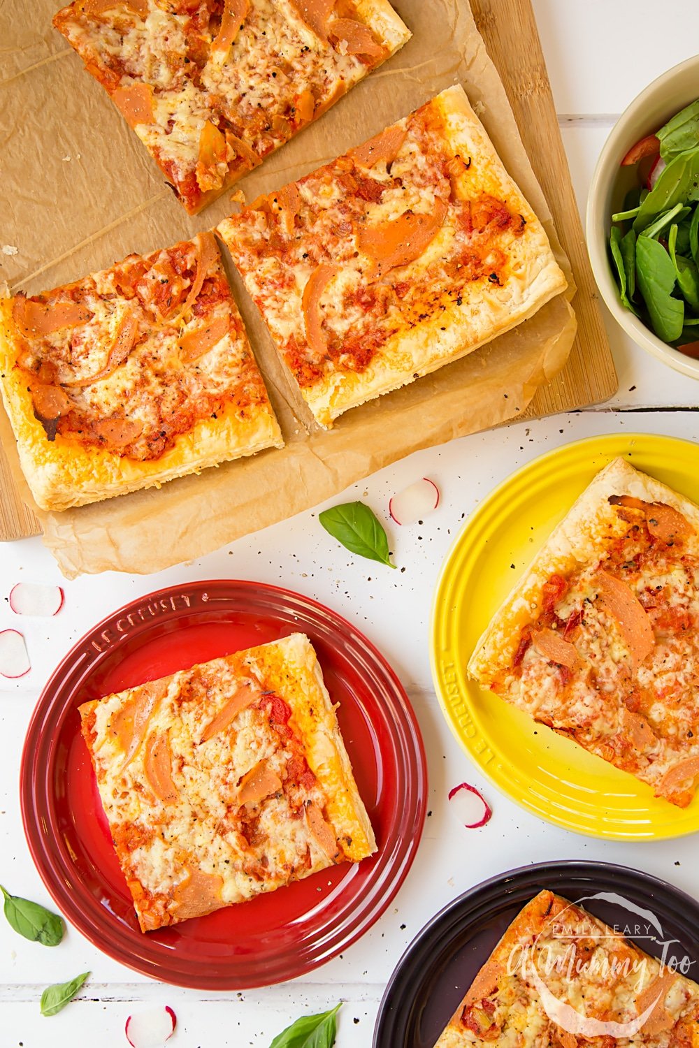 Overhead shot of Pizza style puff pastry slice served on colorful plates with a mummy too logo in the lower-right corner