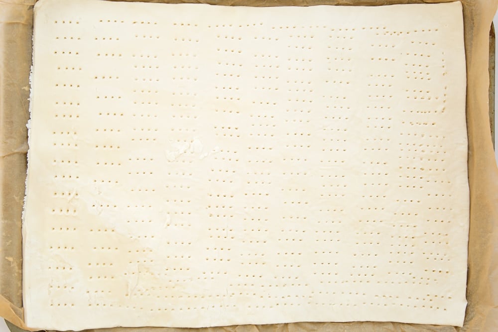 Overhead shot of puff pastry with holes on a baking tray
