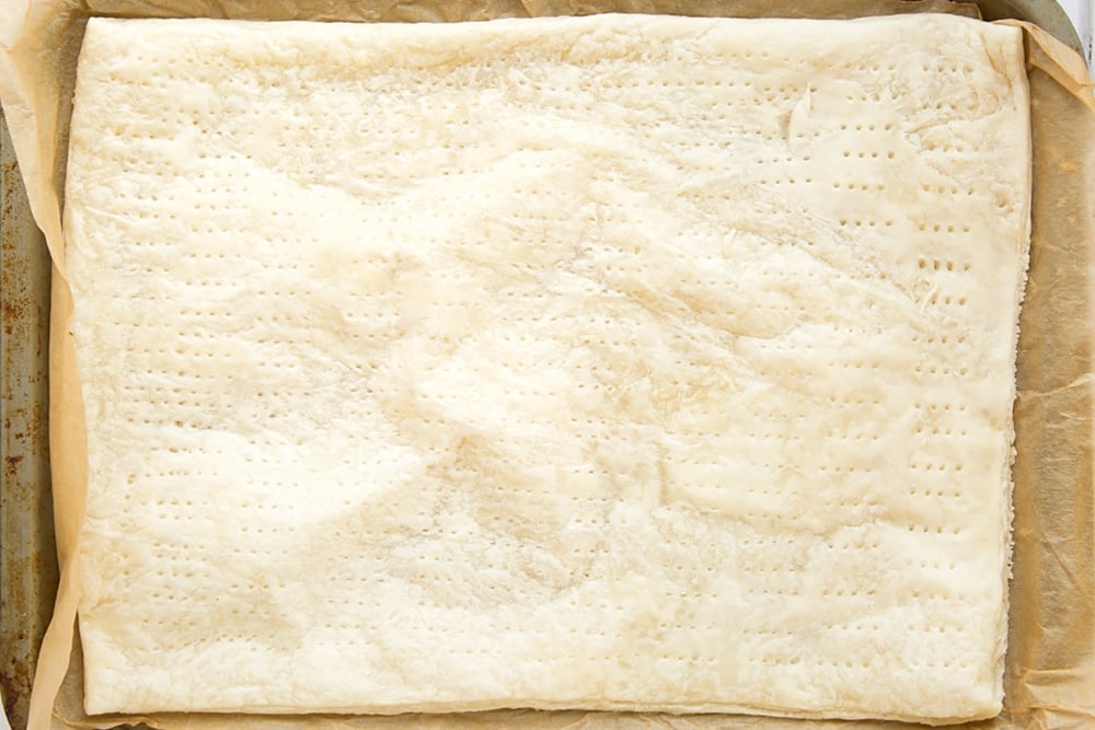 Overhead shot of puffed puff pastry with holes on a baking tray