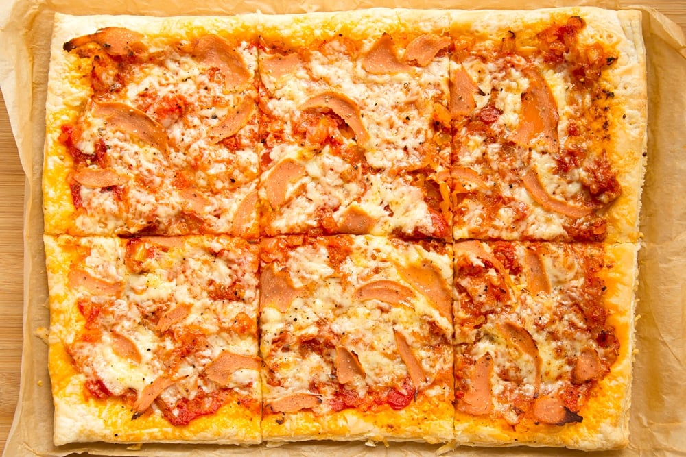 Overhead shot of sliced puff pastry pizza in a baking tray 