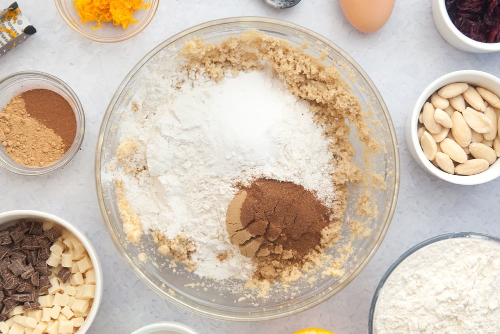 Overhead shot of flour, baking powder, ginger and cinnamon in a large clear bowl