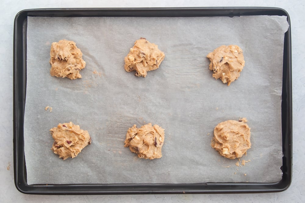 Overhead shot of Cranberry orange white chocolate cookies on a baking rack with a mummy too logo in the lower-left corner