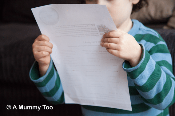 a child ina stripey top reading a piece on paper