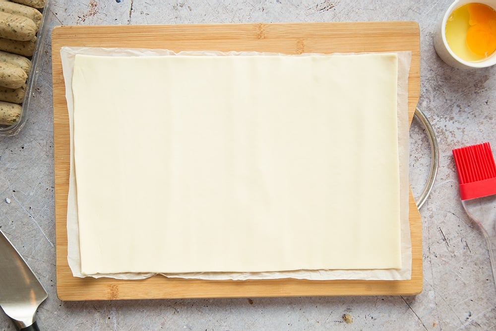 A sheet of puff pastry on a chopping board.