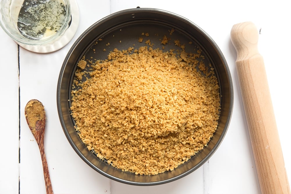 Crumbled biscuits combined with melted butter, tipped into a baking tin.