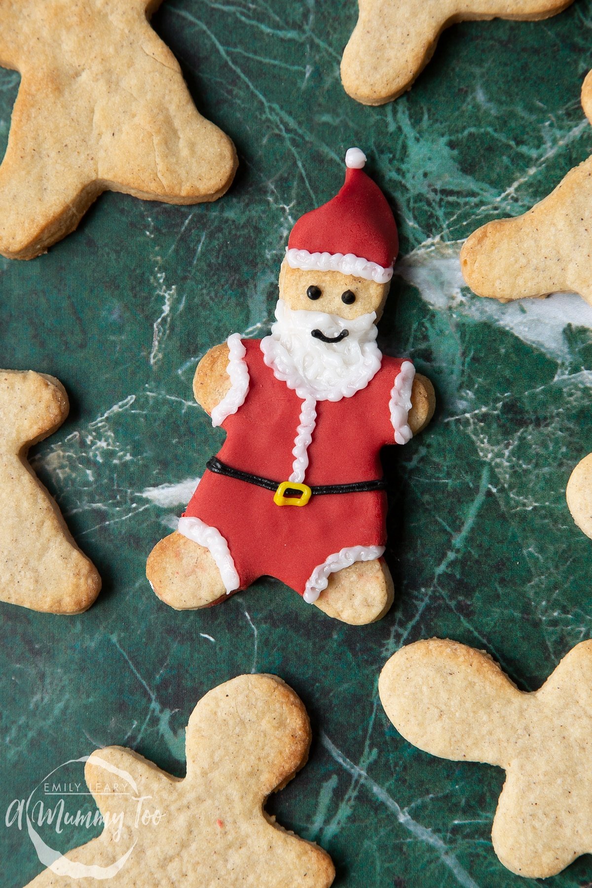 A Father Christmas cookie, decorated with a suit and hat made from red sugar paste and writing icing.