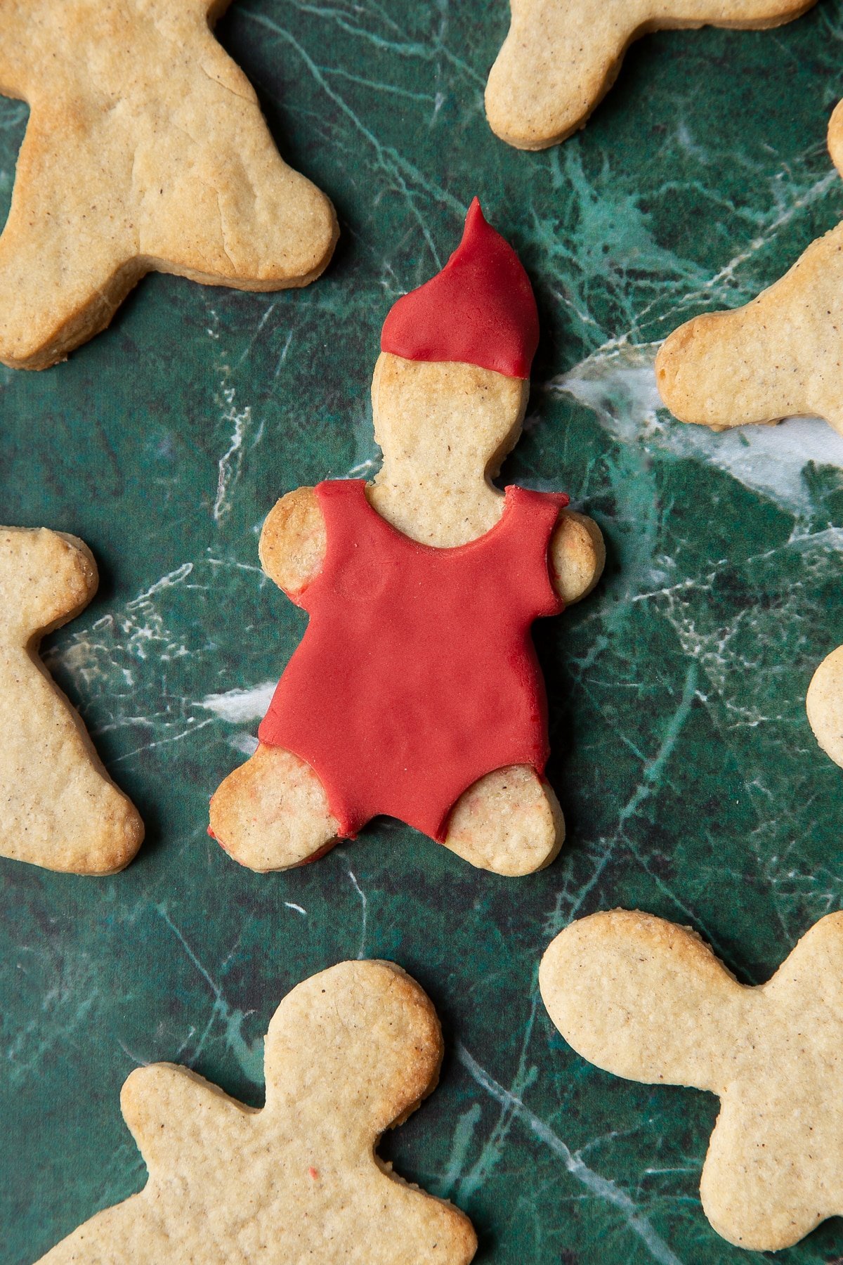 A cookie in the shape of a man, decorated with a suit and hat made from red sugar paste.