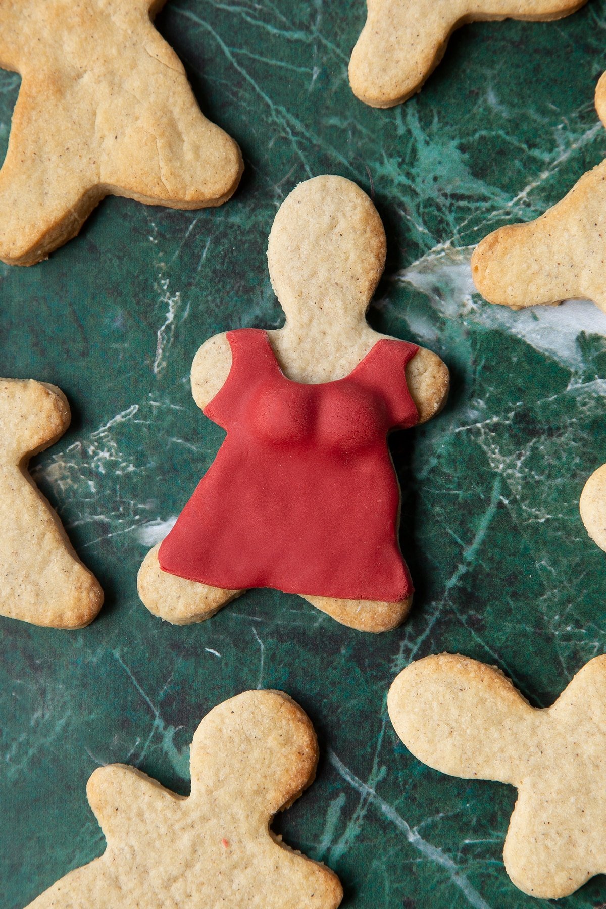 A cookie in the shape of a woman, decorated with a dress made from red sugar paste.