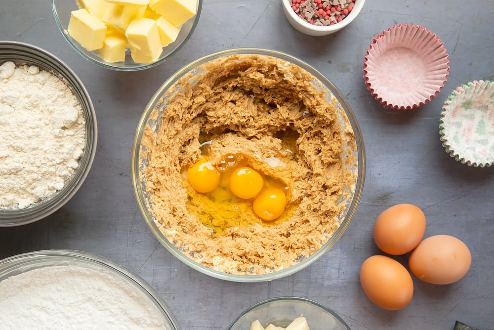 Overhead shot of the sponge ingredients in a pyrex bowl with three eggs on the top. 