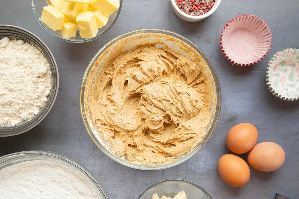 Overhead shot of the sponge ingredients mixed together in a bowl on a grey table. 