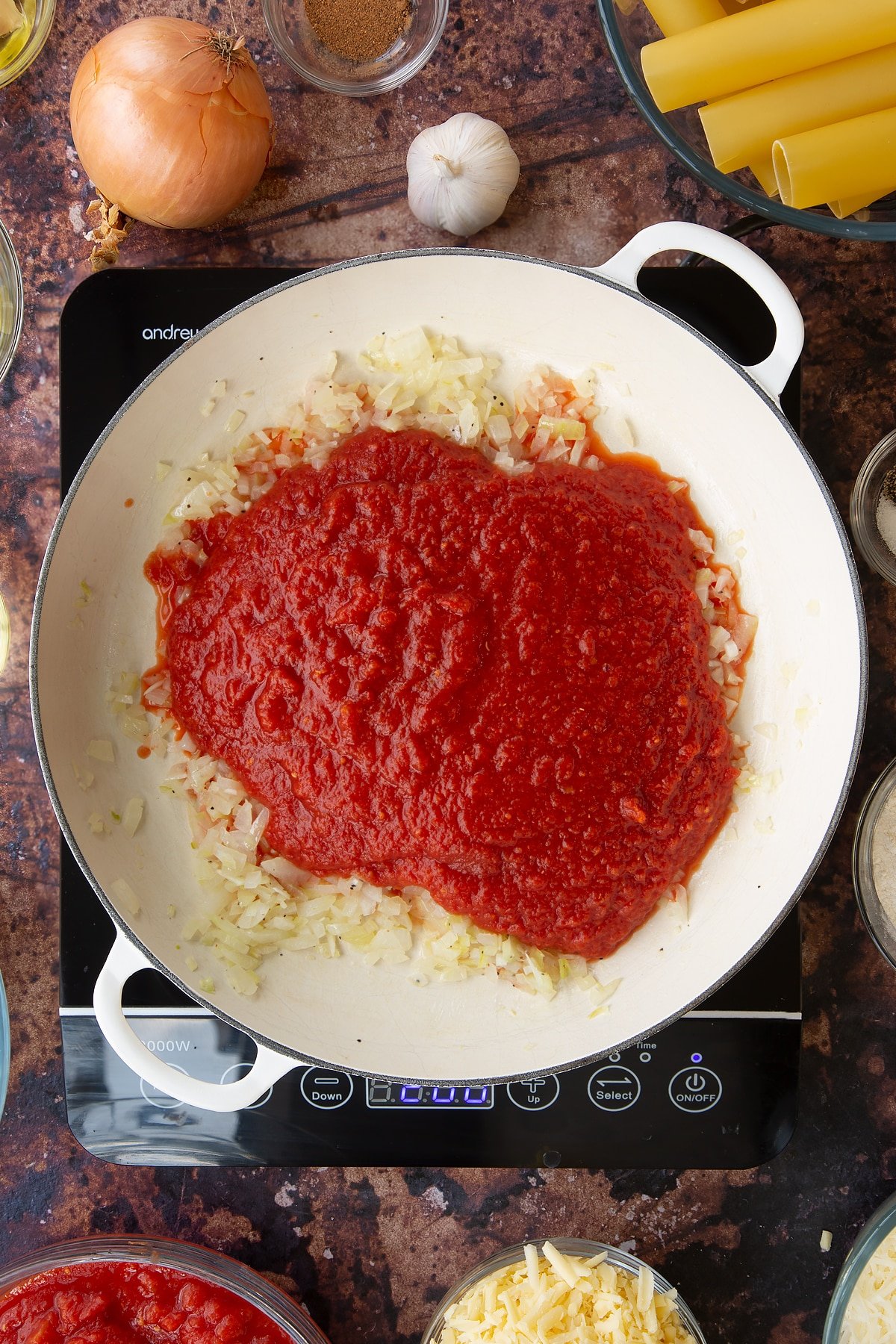 Overhead shot of some of the ingredients required to make the Spinach and ricotta cannelloni in a pan being cooked on an induction hob.