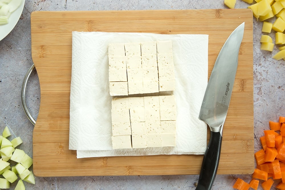 Overhead shot of sliced tofu placed on some kitchen towel on a wooden board 