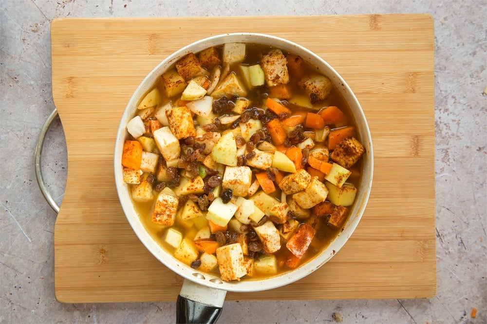 Overhead shot of vegetables with stock in a large white pan