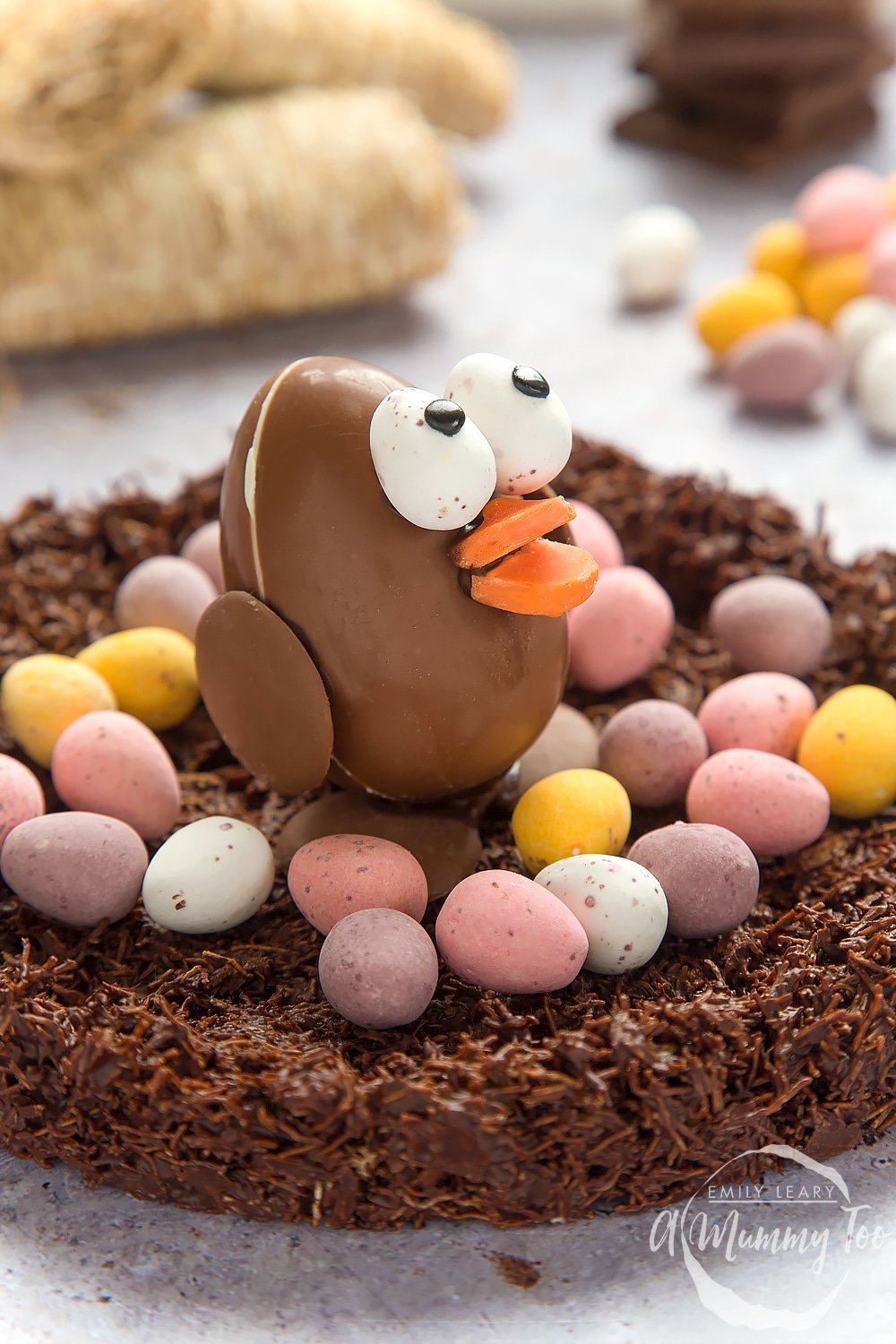 side angle shot Easter chocolate egg chick in a wheaty chocolate nest with a mummy too logo in the lower-right corner