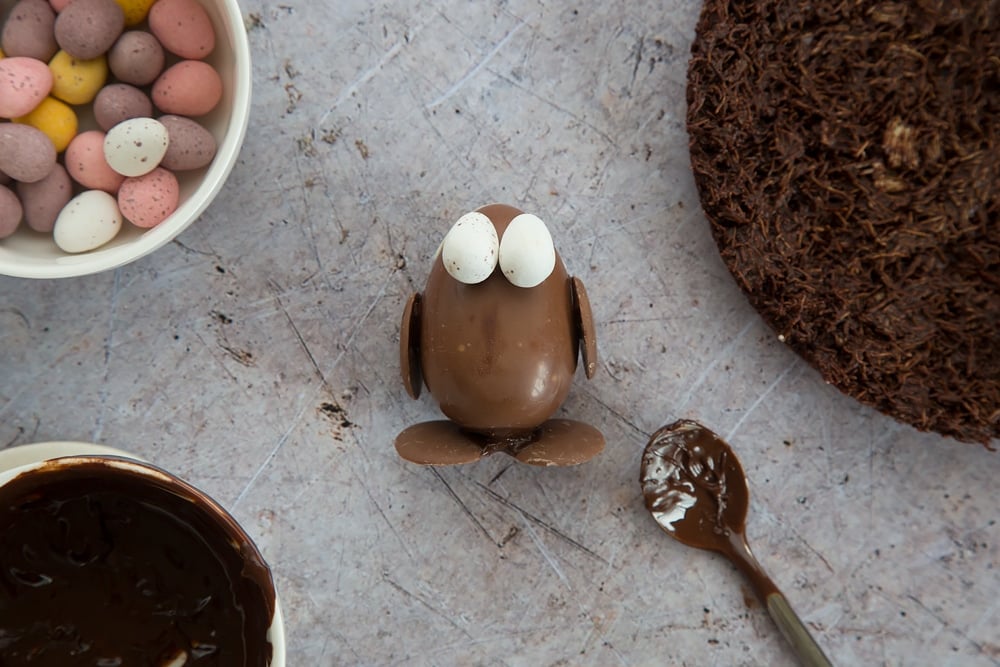 Easter egg chocolate chick shown lying on a table, surrounded by mini eggs