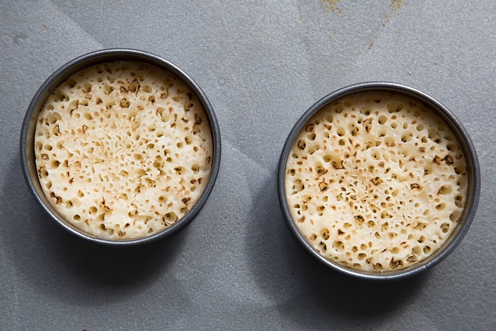 Overhead shot of two egg rings with crumpets inside. 