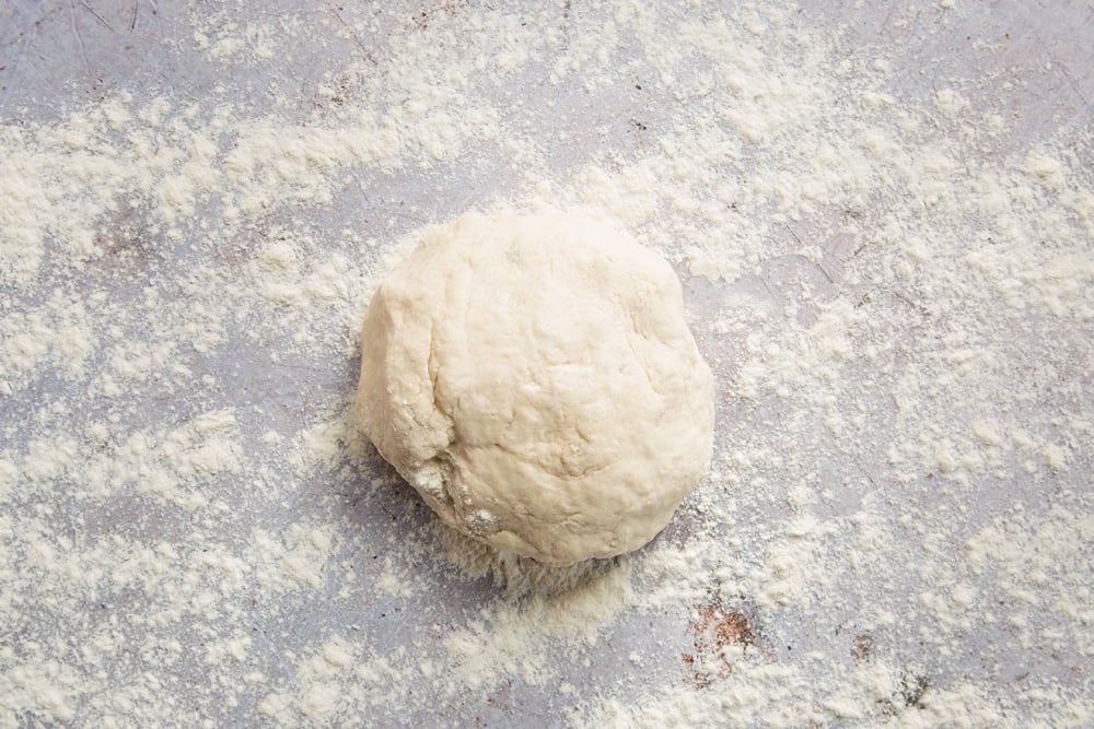 a white flour dough ball placed on a flour dusted surface