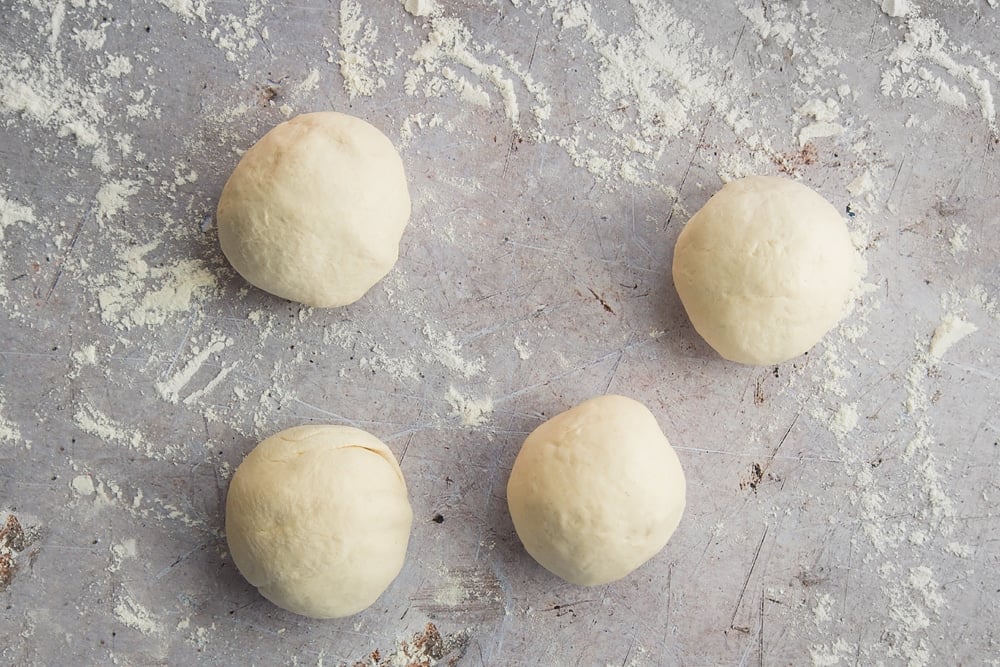 a smooth dough ball  cut into four smaller dough balls on a floured surface.