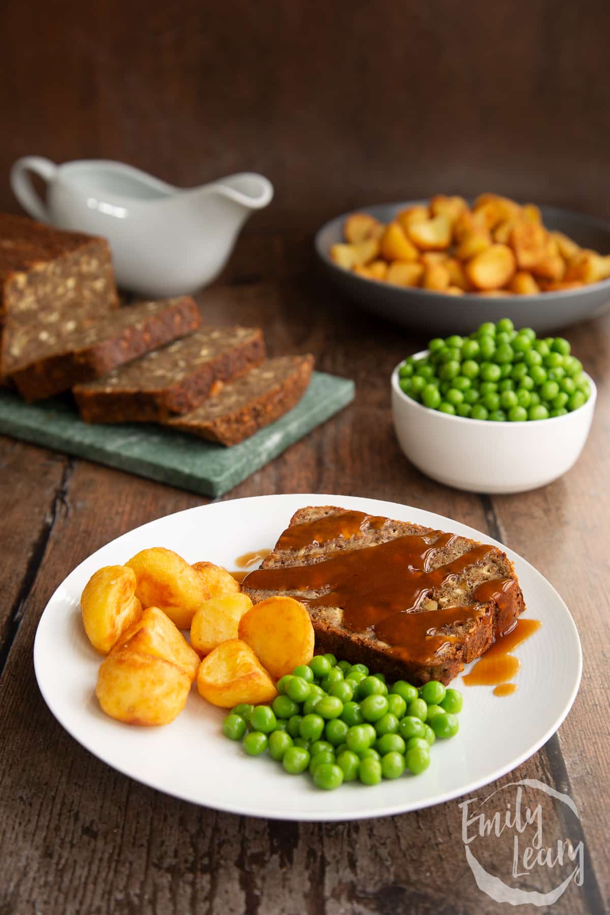 Side on shot of the special k roast on a white plate served with peas and roast potatoes.