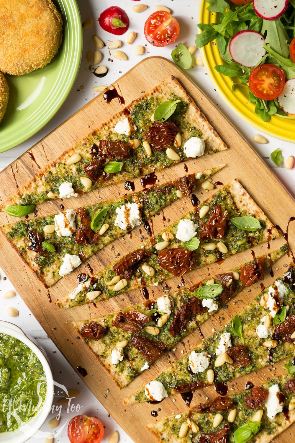 Pesto flatbread pizza topped with goat's cheese, pine nuts and sundried tomatoes