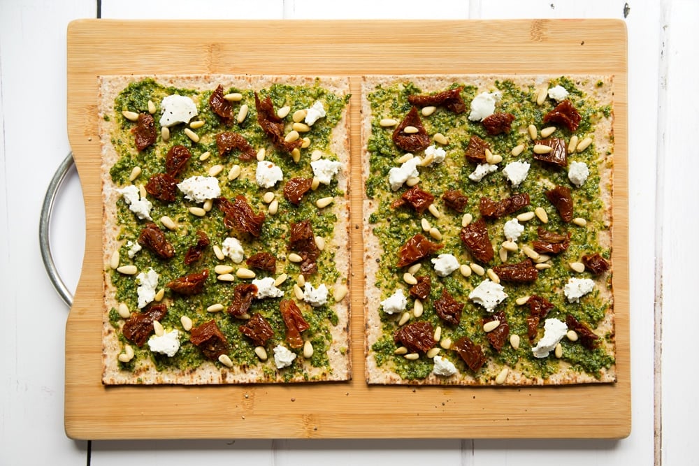 Top the pesto flatbread pizzas with goats cheese, sundried tomatoes and pine nuts