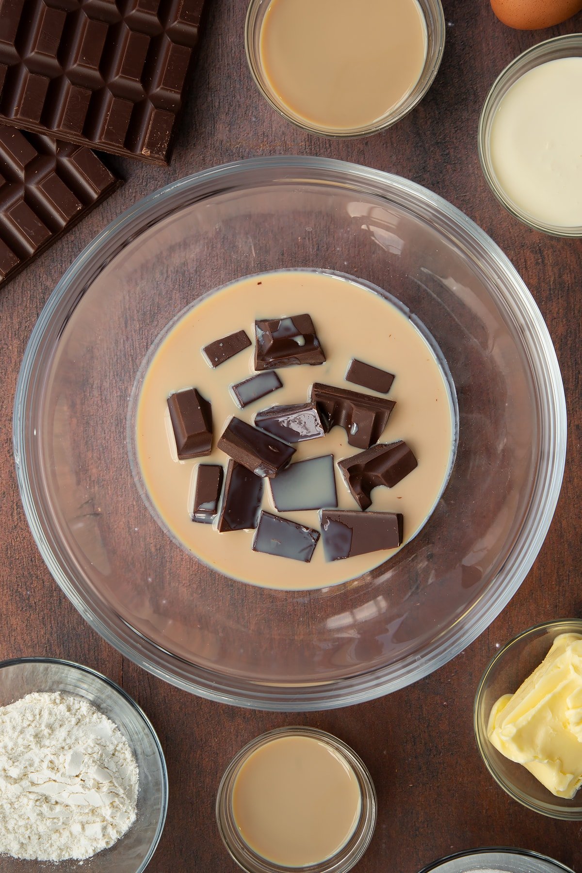 chocolate, cream and Baileys in a clear bowl surrounded by ingredients.