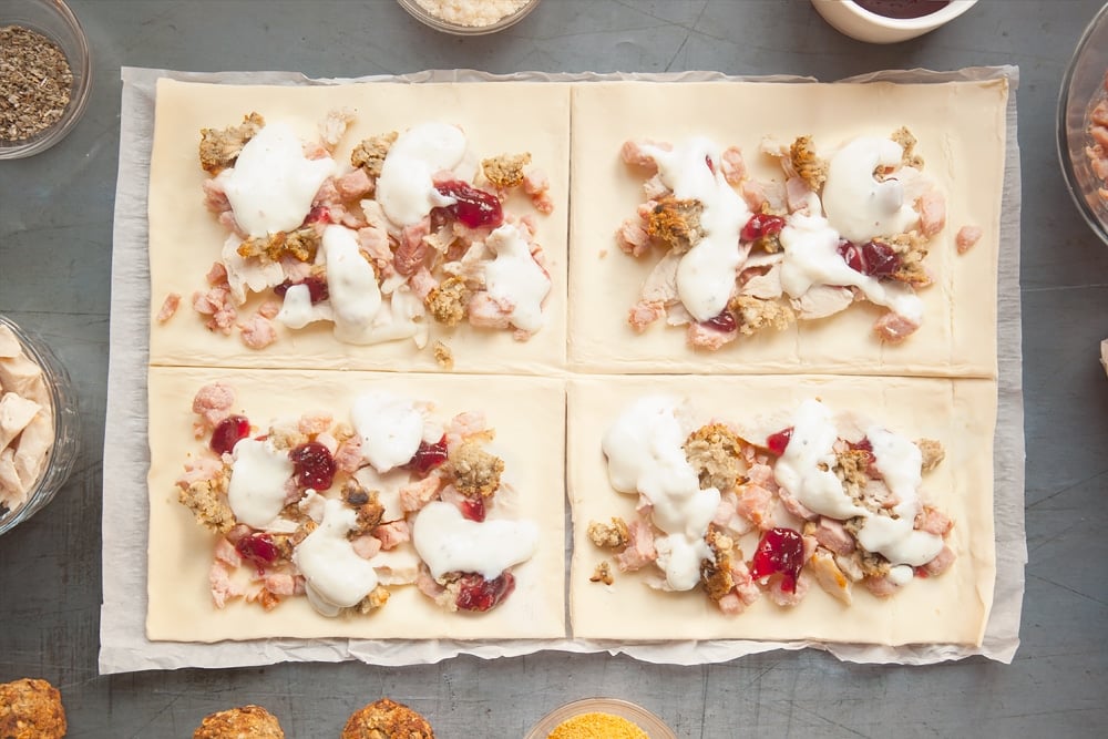 Adding the white sauce to the pastry sheet squares.