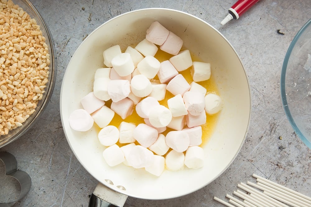 Marshmellows being stirred into a pan. At the side there's some rice crispy's - one of the ingredients required to make heart shaped crispy cake pops.