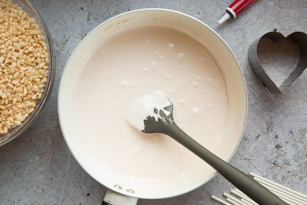 Melted marshmallows mixed with melted butter inside a pan ready to make heart shaped crispy cake pops.