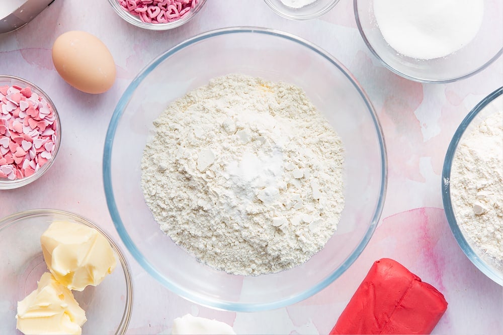 Overhead shot of flour, baking powder, salt and bicarbonate of soda in a large clear bowl