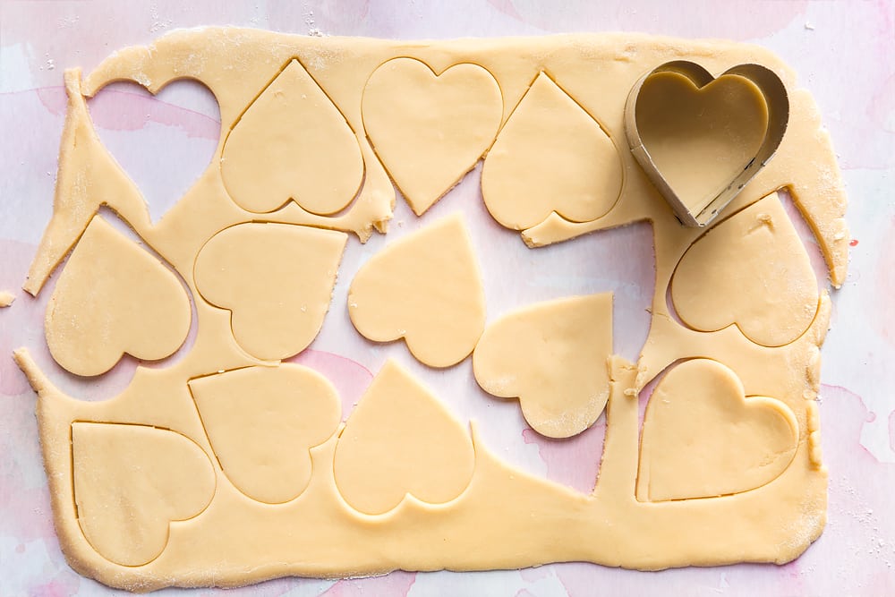 Overhead shot of rolled out cookie dough with heart cutouts