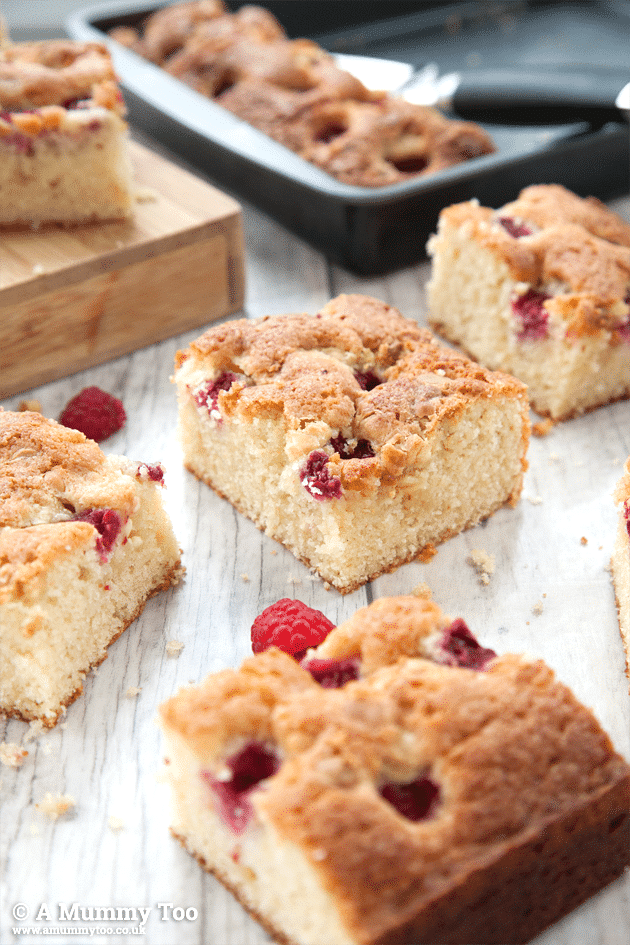 Raspberry and white chocolate traybake cut into squares on a light wooden surface
