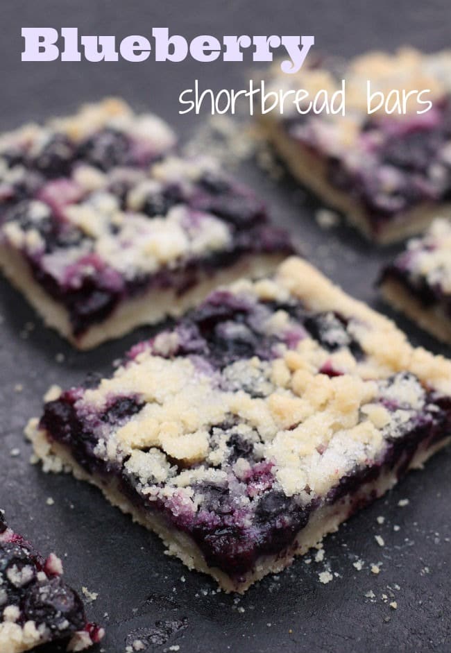 Blueberry Shortbread Bars cut into squares on a black surface.
