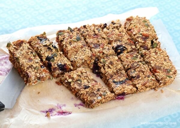 slices of fruity Granola Bars on a piece of greaseproof paper with a knife on the side.