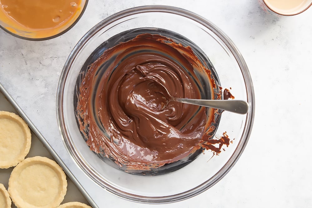 Melting dark chocolate for the next layer of these Baileys salted caramel mini chocolate tarts