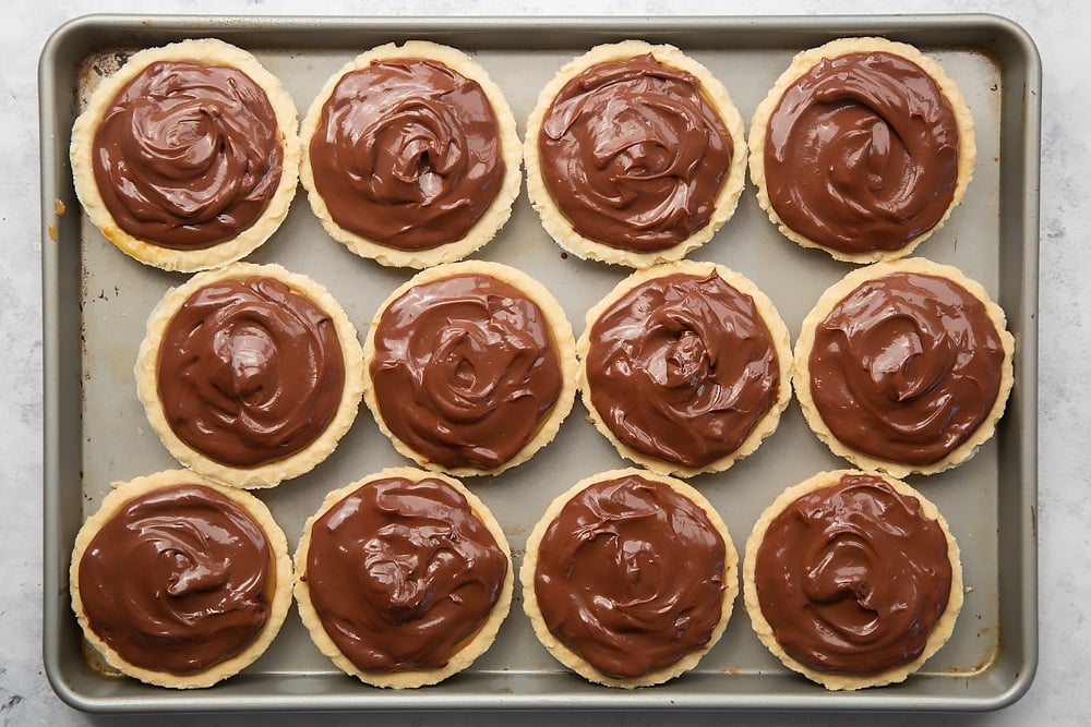 Topping the Baileys salted caramel mini chocolate tarts with chocolate ganache