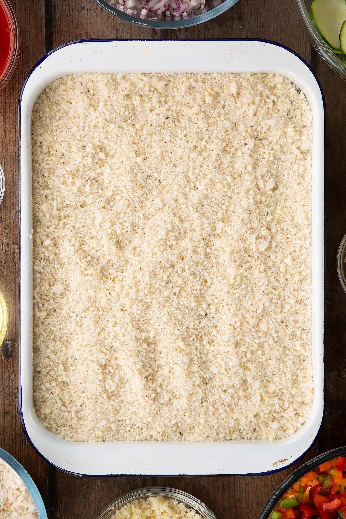 breadcrumb topping on a courgette and tomato base in a white baking dish.