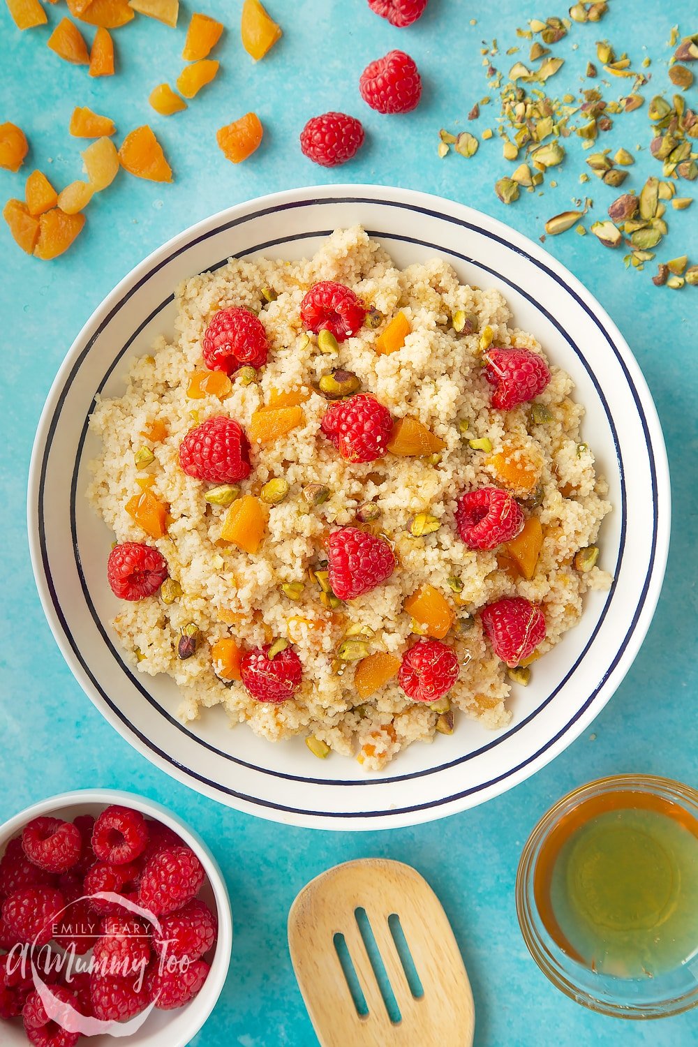 Overhead shot of the sweet breakfast couscous in a white bowl with black decoation. At the side of the bowl there's some of the ingredients required for the recipe. 