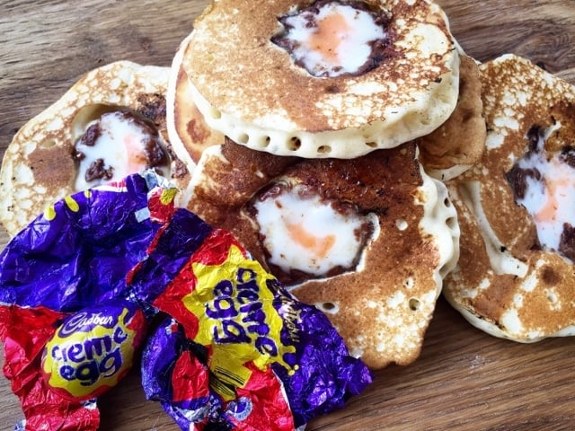 cream egg pancakes laid out on a wooden surface with a cabburys creme egg wrapper to the side.