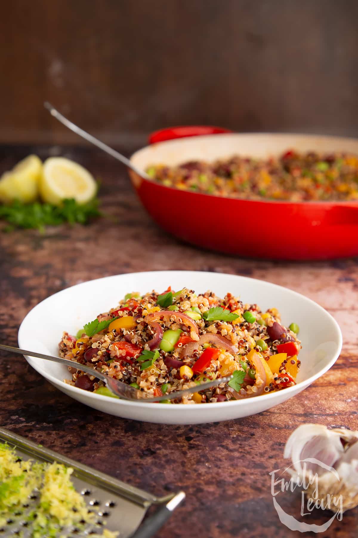 A bowl of Zesty bean quinoa with a fork on the side sitting on a wodden table.