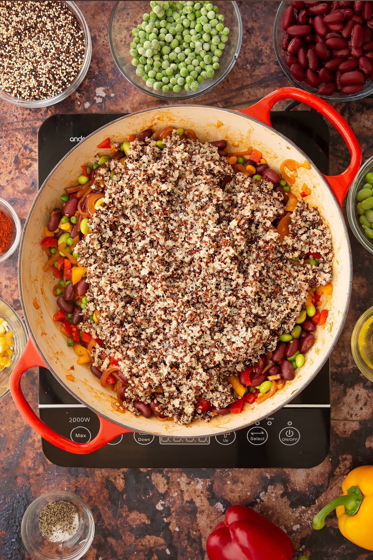 Overhead shot of some of the ingredients required to make the Zesty bean quinoa in a pan on the hob.