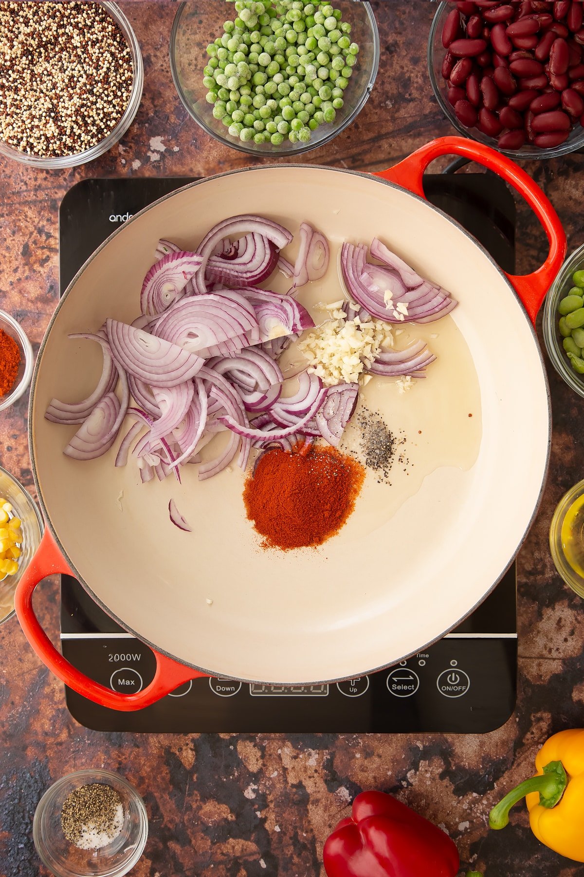 Overhead shot of some of the ingredients required to make the Zesty bean quinoa in a pan on the hob.