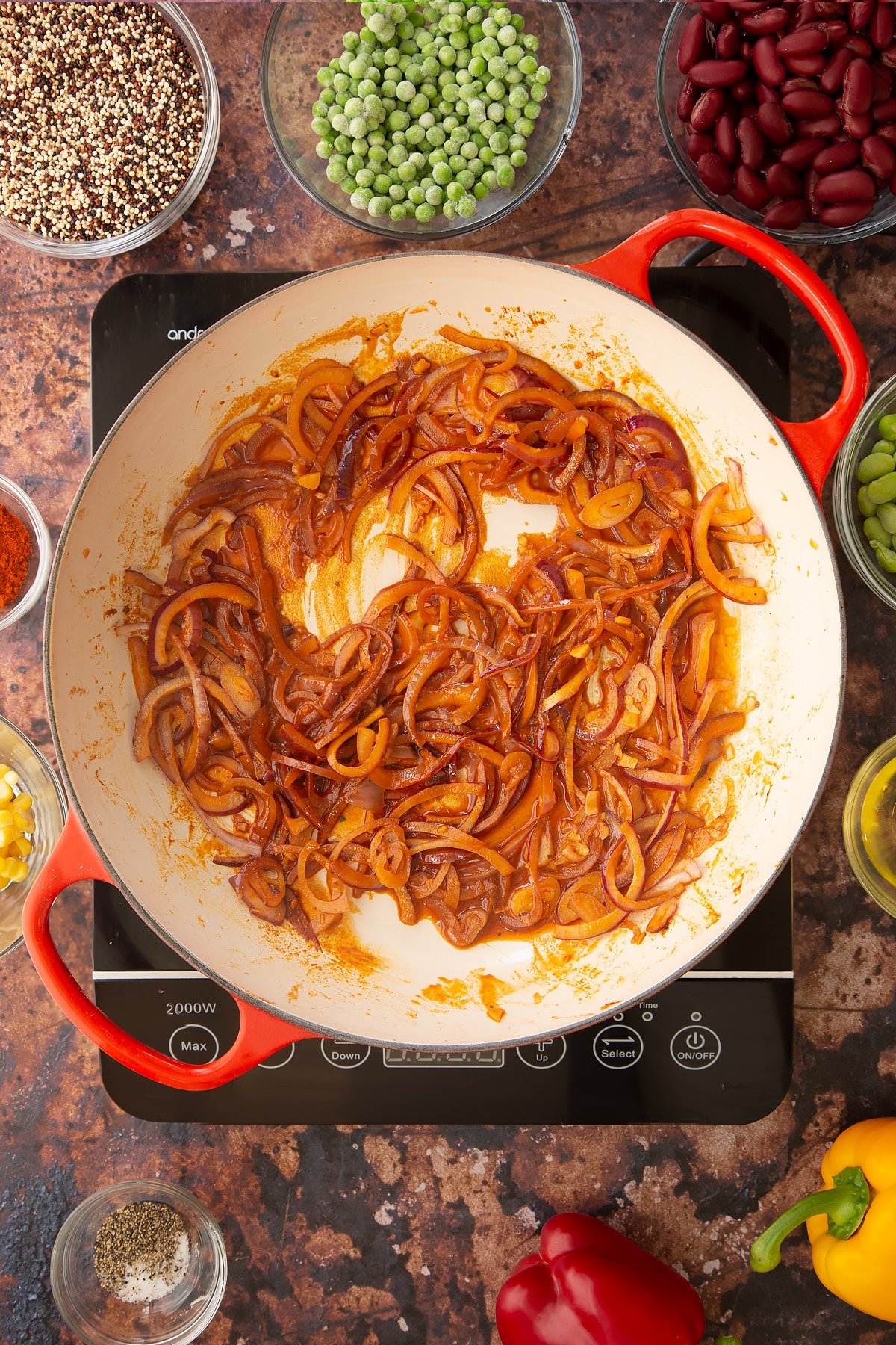 Overhead shot of some of the ingredients required to make the Zesty bean quinoa in a pan on the hob.