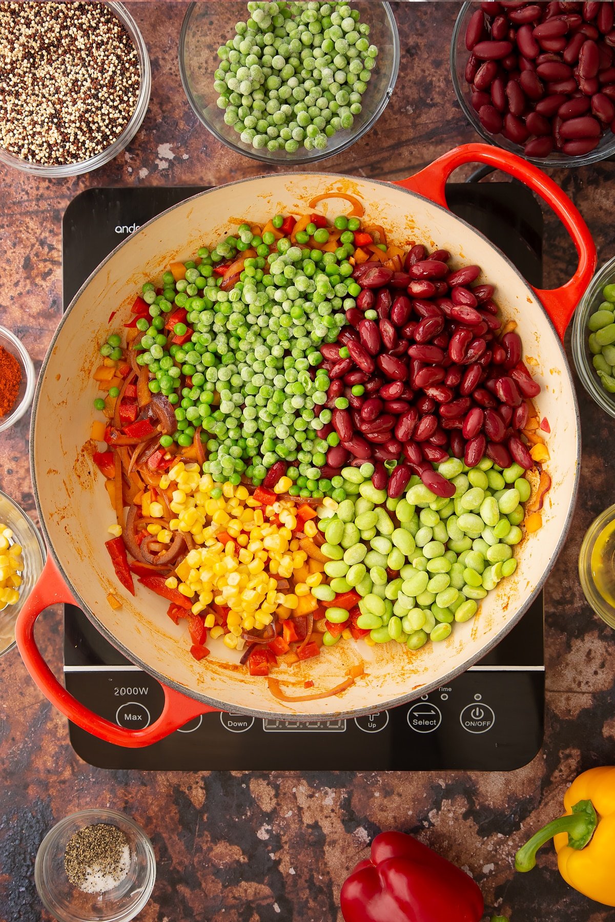 Overhead shot of some of the ingredients required to make the Zesty bean quinoa in a pan on the hob.